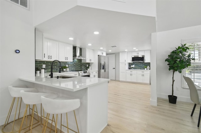 14170 Fennsbury Dr, Tampa, FL 33624 - kitchen with appliances with stainless steel finishes, a sink, decorative backsplash, a peninsula, and light wood-type flooring