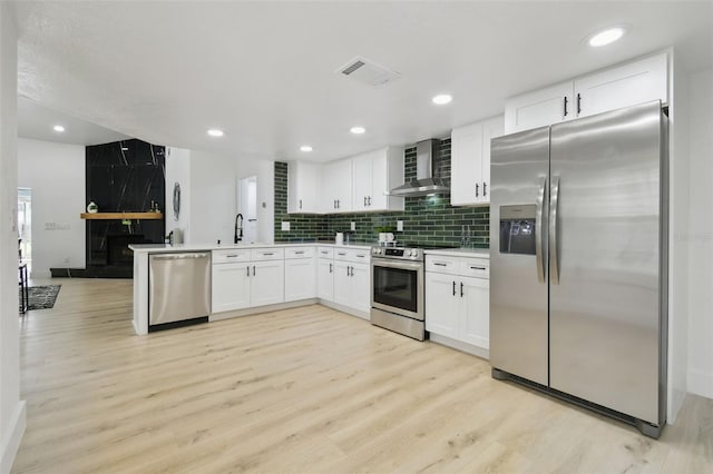 14170 Fennsbury Dr, Tampa, FL 33624 - kitchen featuring stainless steel appliances, wall chimney exhaust hood, light wood-type flooring, white cabinetry, and backsplash