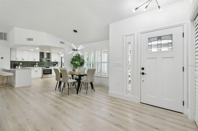 14170 Fennsbury Dr, Tampa, FL 33624 - foyer entrance with light wood-style flooring, vaulted ceiling, a chandelier, and baseboards