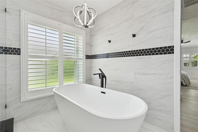 14170 Fennsbury Dr, Tampa, FL 33624 - full bath with tile walls, a freestanding tub, marble finish flooring, and a chandelier