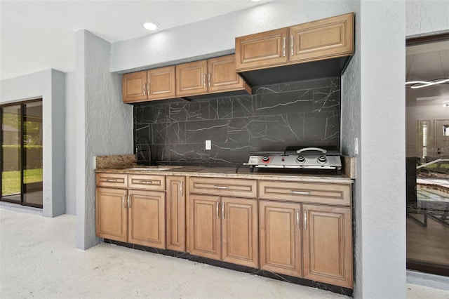 14170 Fennsbury Dr, Tampa, FL 33624 - kitchen featuring a sink, brown cabinets, tasteful backsplash, and stone countertops
