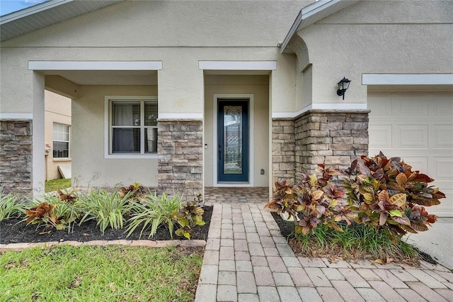 property entrance with stone siding, stucco siding, a garage, and a porch
