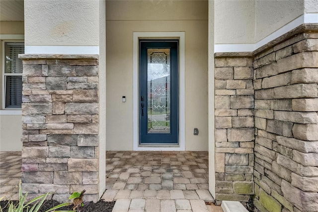 doorway to property with stucco siding and stone siding