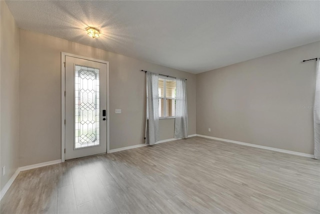 entryway with light wood-style floors, baseboards, and a textured ceiling