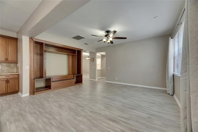 unfurnished living room featuring a ceiling fan, light wood finished floors, and baseboards