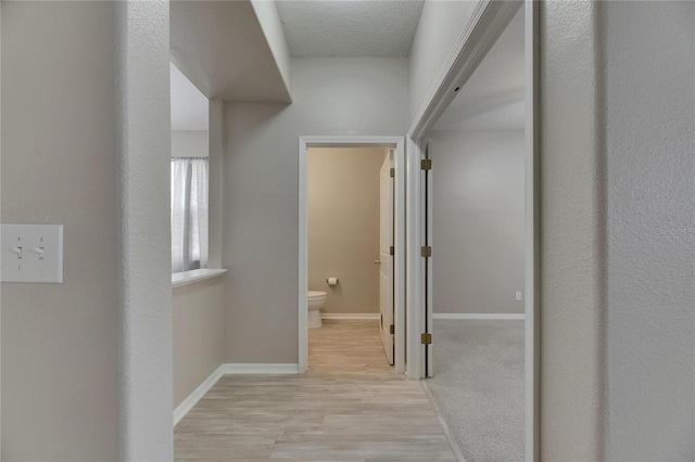 hall with light wood-style floors and baseboards
