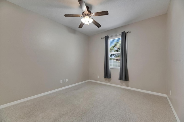 spare room with light colored carpet, baseboards, and a ceiling fan