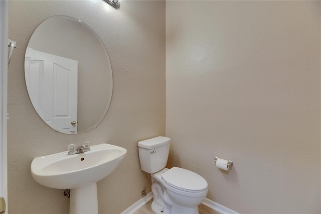 bathroom featuring toilet, a sink, and baseboards