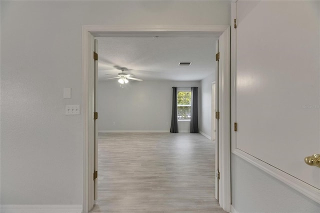 hall featuring light wood-style flooring and baseboards