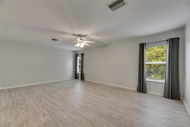 unfurnished room featuring ceiling fan, light wood finished floors, a textured ceiling, and baseboards