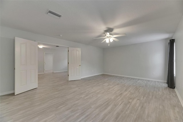 spare room featuring a ceiling fan, light wood-style floors, and baseboards