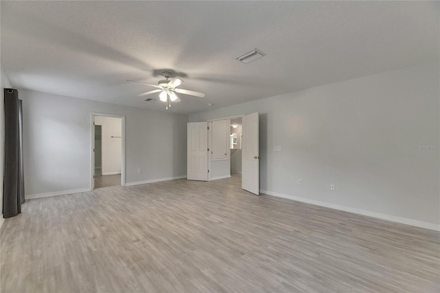 empty room featuring a ceiling fan, light wood-style floors, baseboards, and a textured ceiling
