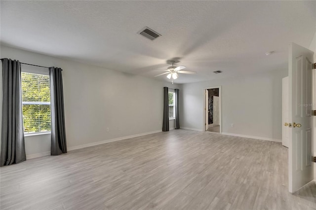 empty room featuring ceiling fan, light wood-style flooring, a textured ceiling, and baseboards