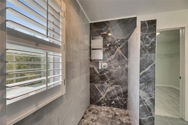 full bath with a tile shower and a spacious closet