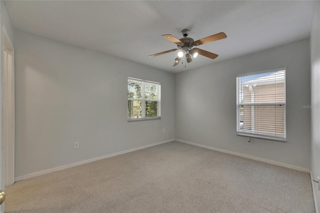 carpeted empty room featuring a ceiling fan and baseboards