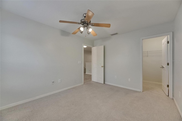 unfurnished bedroom featuring a spacious closet, light colored carpet, baseboards, and a closet