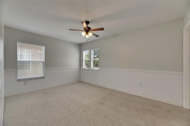 unfurnished room featuring a ceiling fan, wainscoting, carpet floors, and a textured ceiling