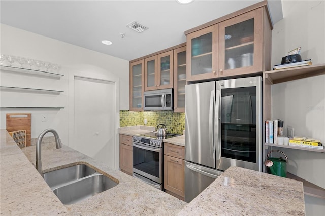 1010 Central Ave Unit 227, Saint Petersburg, FL 33705 - kitchen featuring stainless steel appliances, a sink, light stone counters, tasteful backsplash, and glass insert cabinets