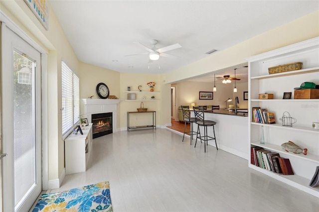 71 Flamingo Cir, Safety Harbor, FL 34695 - living room featuring a ceiling fan, a glass covered fireplace, baseboards, and wood finished floors