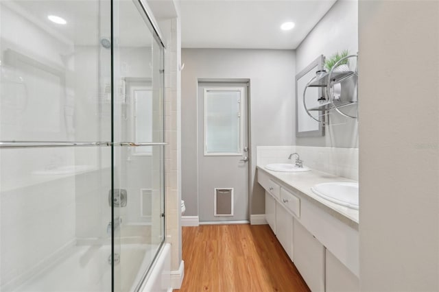 71 Flamingo Cir, Safety Harbor, FL 34695 - bathroom with double vanity, wood finished floors, toilet, backsplash, and enclosed tub / shower combo