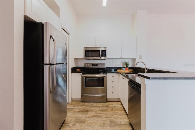18107 Peregrines Perch Pl Unit 6303, Lutz, FL 33558 - kitchen with appliances with stainless steel finishes, dark countertops, light wood-type flooring, white cabinets, and a peninsula