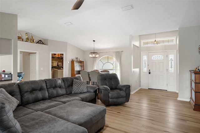 1854 S Overview Dr, Lecanto, FL 34461 - living room featuring light wood finished floors, a chandelier, baseboards, vaulted ceiling, and separate washer and dryer