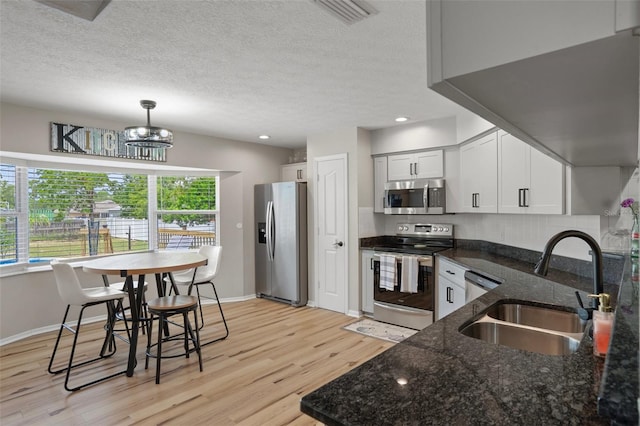 1854 S Overview Dr, Lecanto, FL 34461 - kitchen featuring stainless steel appliances, a sink, light wood finished floors, a textured ceiling, and baseboards