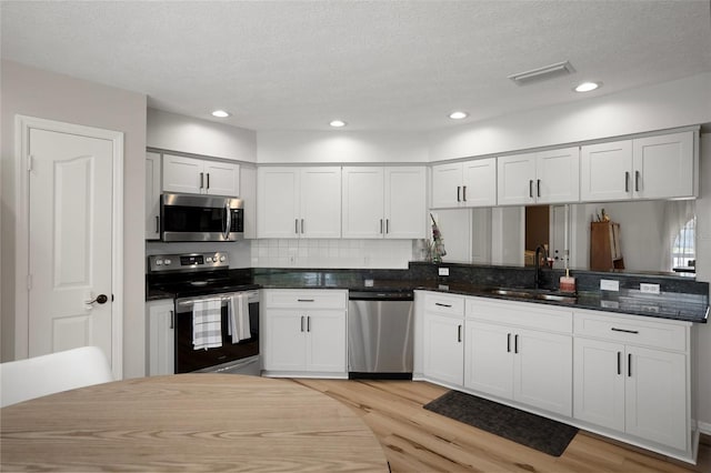 1854 S Overview Dr, Lecanto, FL 34461 - kitchen with appliances with stainless steel finishes, a sink, light wood-style floors, tasteful backsplash, and a textured ceiling