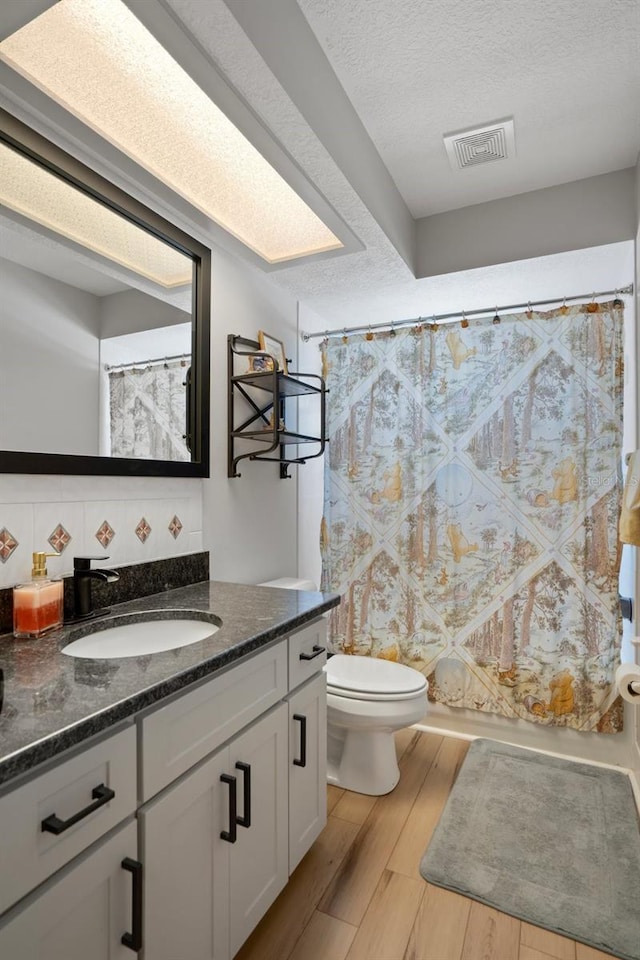 1854 S Overview Dr, Lecanto, FL 34461 - bathroom featuring wood finished floors, toilet, vanity, a textured ceiling, and decorative backsplash