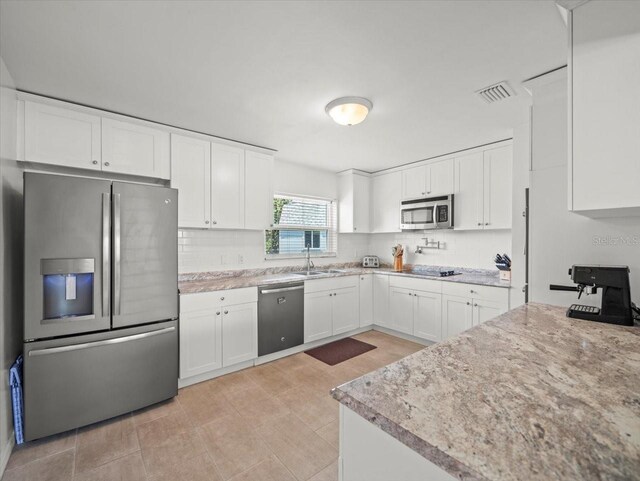 4005 W Coachman Ave, Tampa, FL 33611 - kitchen with appliances with stainless steel finishes, a sink, tasteful backsplash, and white cabinetry