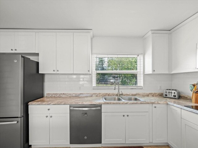 4005 W Coachman Ave, Tampa, FL 33611 - kitchen with appliances with stainless steel finishes, a sink, white cabinets, and backsplash