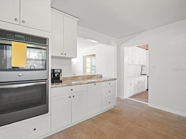 4005 W Coachman Ave, Tampa, FL 33611 - kitchen featuring stainless steel double oven, white cabinets, baseboards, and light wood finished floors