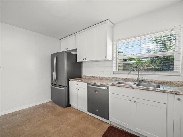 4005 W Coachman Ave, Tampa, FL 33611 - kitchen with appliances with stainless steel finishes, a sink, white cabinets, tasteful backsplash, and baseboards
