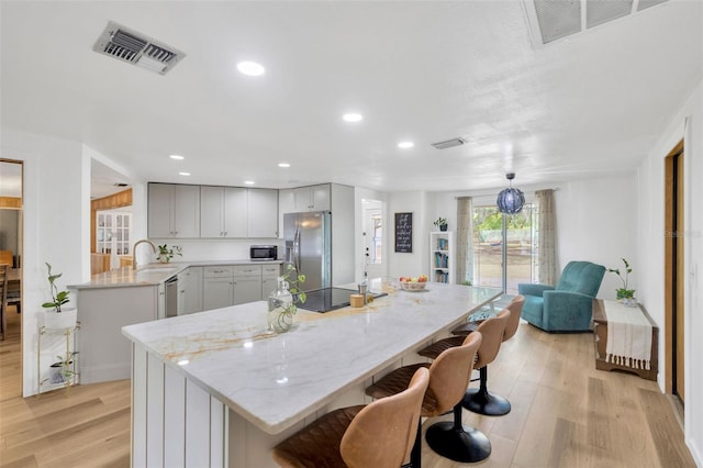 525 Gornto Lake Rd, Brandon, FL 33510 - kitchen featuring appliances with stainless steel finishes, light wood-style floors, a kitchen breakfast bar, light stone countertops, and a sink