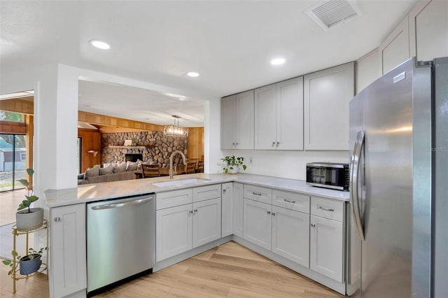 525 Gornto Lake Rd, Brandon, FL 33510 - kitchen featuring stainless steel appliances, a sink, light countertops, a fireplace, and light wood-style floors