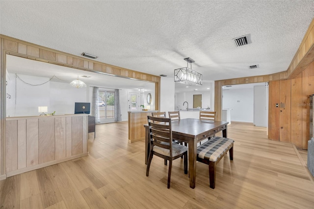 525 Gornto Lake Rd, Brandon, FL 33510 - dining area with wooden walls, light wood-style floors, a textured ceiling, and a chandelier