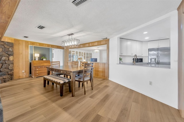 525 Gornto Lake Rd, Brandon, FL 33510 - dining space featuring a chandelier, wooden walls, a textured ceiling, and light wood-style floors