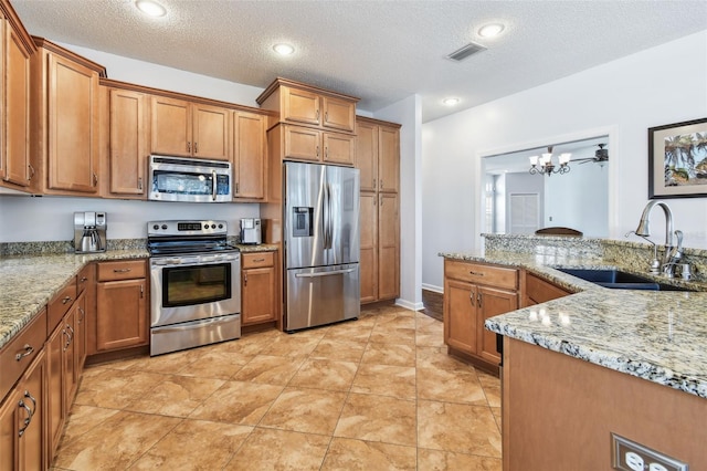 13028 Prestwick Dr, Riverview, FL 33579 - kitchen with stainless steel appliances, a sink, brown cabinets, a textured ceiling, and light stone countertops