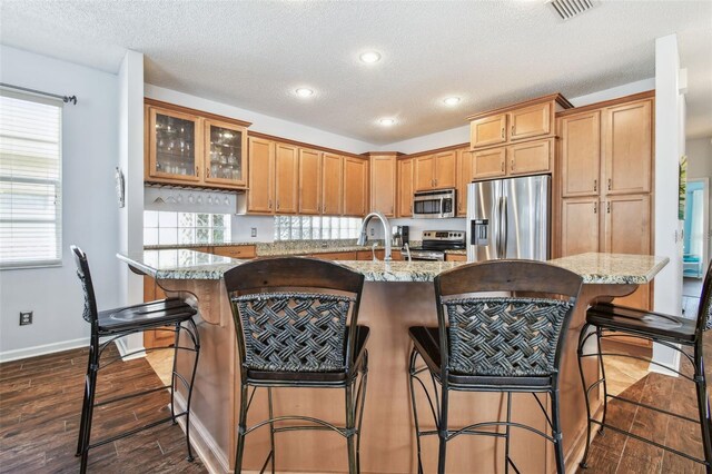 13028 Prestwick Dr, Riverview, FL 33579 - kitchen featuring appliances with stainless steel finishes, a textured ceiling, a breakfast bar area, recessed lighting, and baseboards