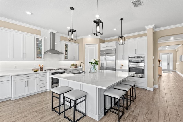 6154 Marsh Trail Dr, Odessa, FL 33556 - kitchen featuring appliances with stainless steel finishes, wall chimney range hood, arched walkways, a sink, and light wood finished floors