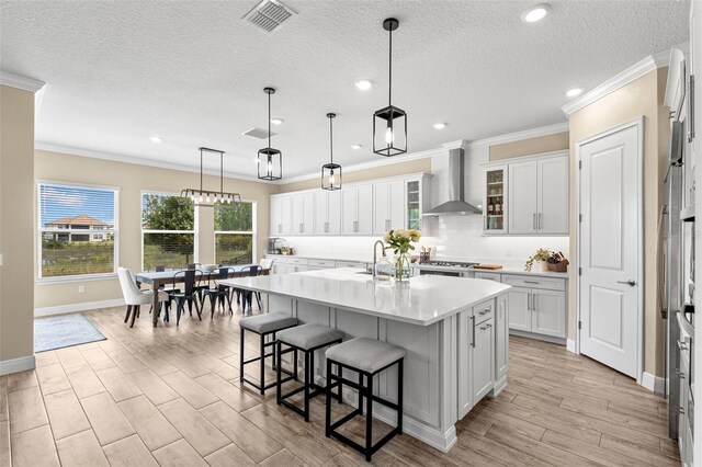 6154 Marsh Trail Dr, Odessa, FL 33556 - kitchen featuring wall chimney exhaust hood, ornamental molding, a kitchen bar, light countertops, and decorative backsplash