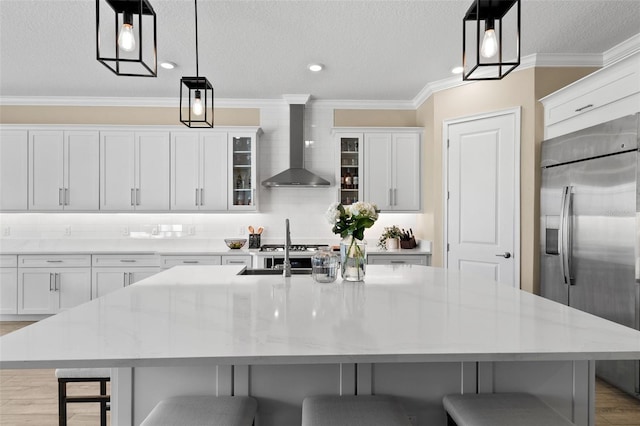 6154 Marsh Trail Dr, Odessa, FL 33556 - kitchen featuring built in refrigerator, wall chimney exhaust hood, ornamental molding, white cabinets, and a spacious island