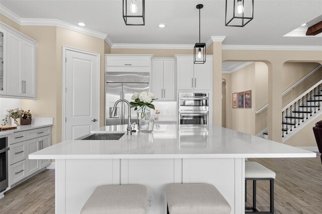 6154 Marsh Trail Dr, Odessa, FL 33556 - kitchen with a sink, appliances with stainless steel finishes, light wood-type flooring, ornamental molding, and a breakfast bar