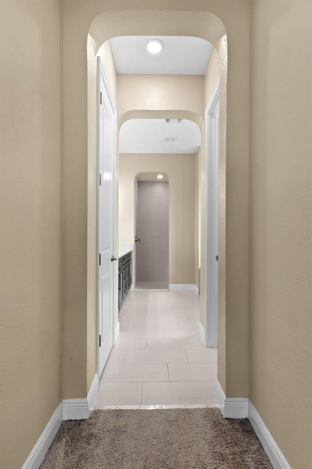 6154 Marsh Trail Dr, Odessa, FL 33556 - hallway with arched walkways, baseboards, light tile patterned floors, and light colored carpet