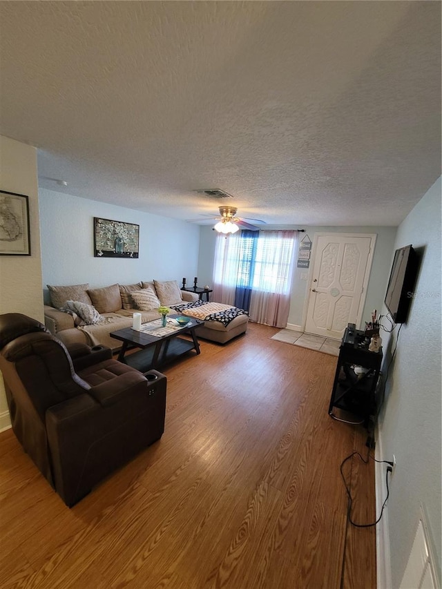 living area with light wood-style floors, a textured ceiling, and ceiling fan