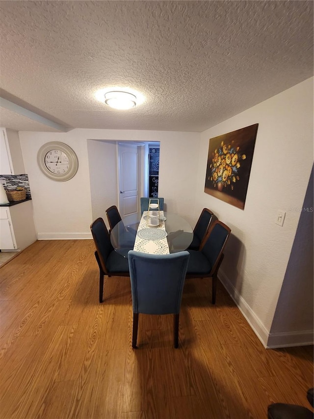 dining area with a textured ceiling, wood finished floors, and baseboards
