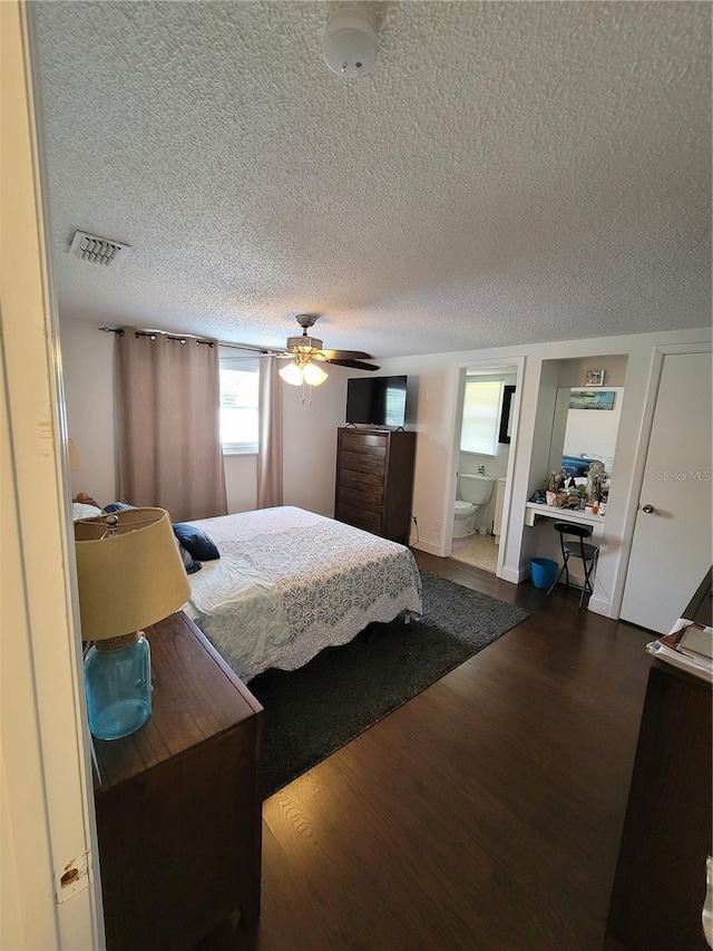 bedroom featuring dark wood-style flooring, a textured ceiling, ensuite bathroom, and ceiling fan