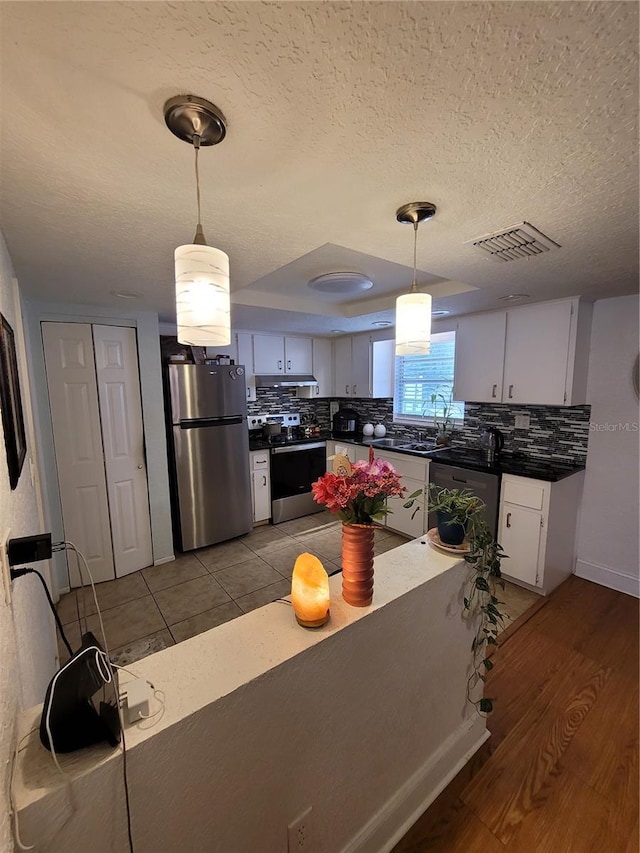 kitchen with appliances with stainless steel finishes, dark countertops, backsplash, and a textured ceiling