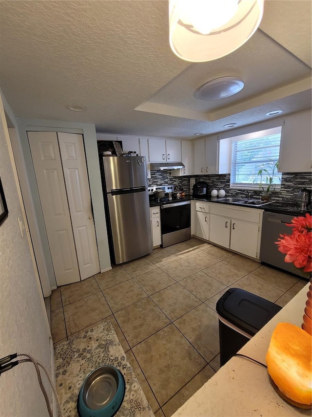 kitchen featuring appliances with stainless steel finishes, white cabinets, tasteful backsplash, light tile patterned floors, and dark countertops