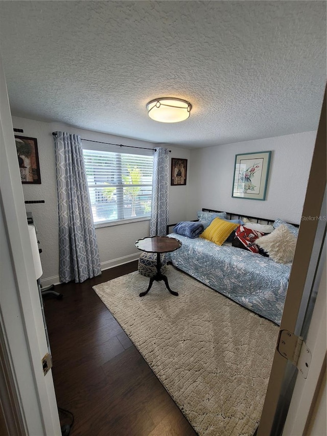 bedroom featuring wood finished floors, a textured ceiling, and baseboards